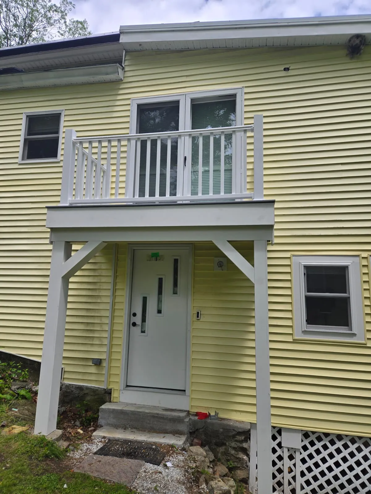 Rebuilt balcony with white railing, knee braces and new entry door