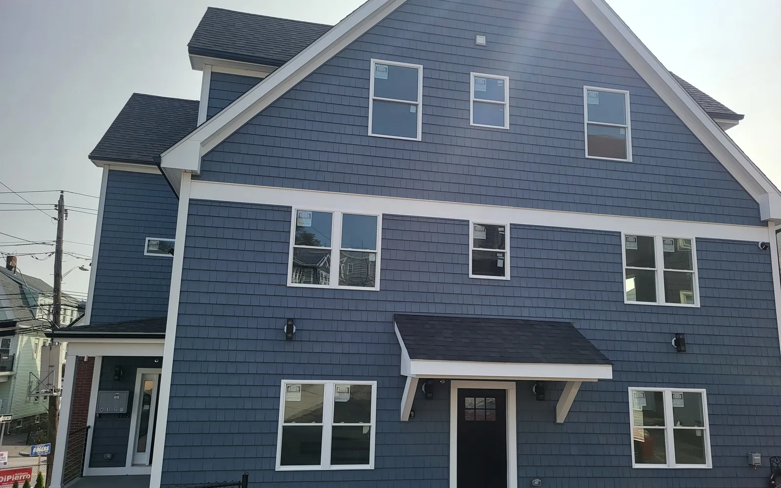 Three-story home with new blue vinyl siding, windows and covered front entry