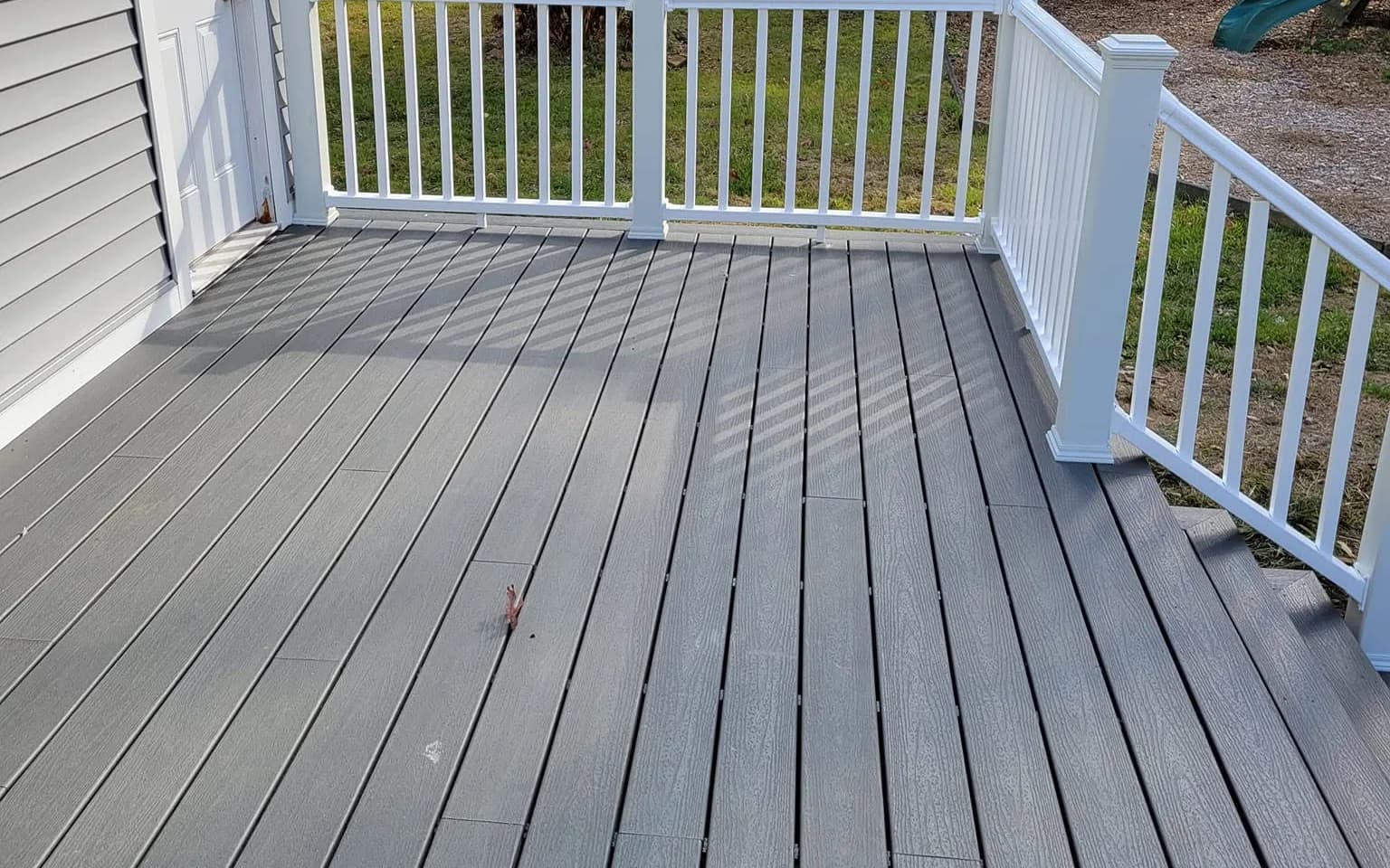 Composite deck with white vinyl railing in a fenced backyard