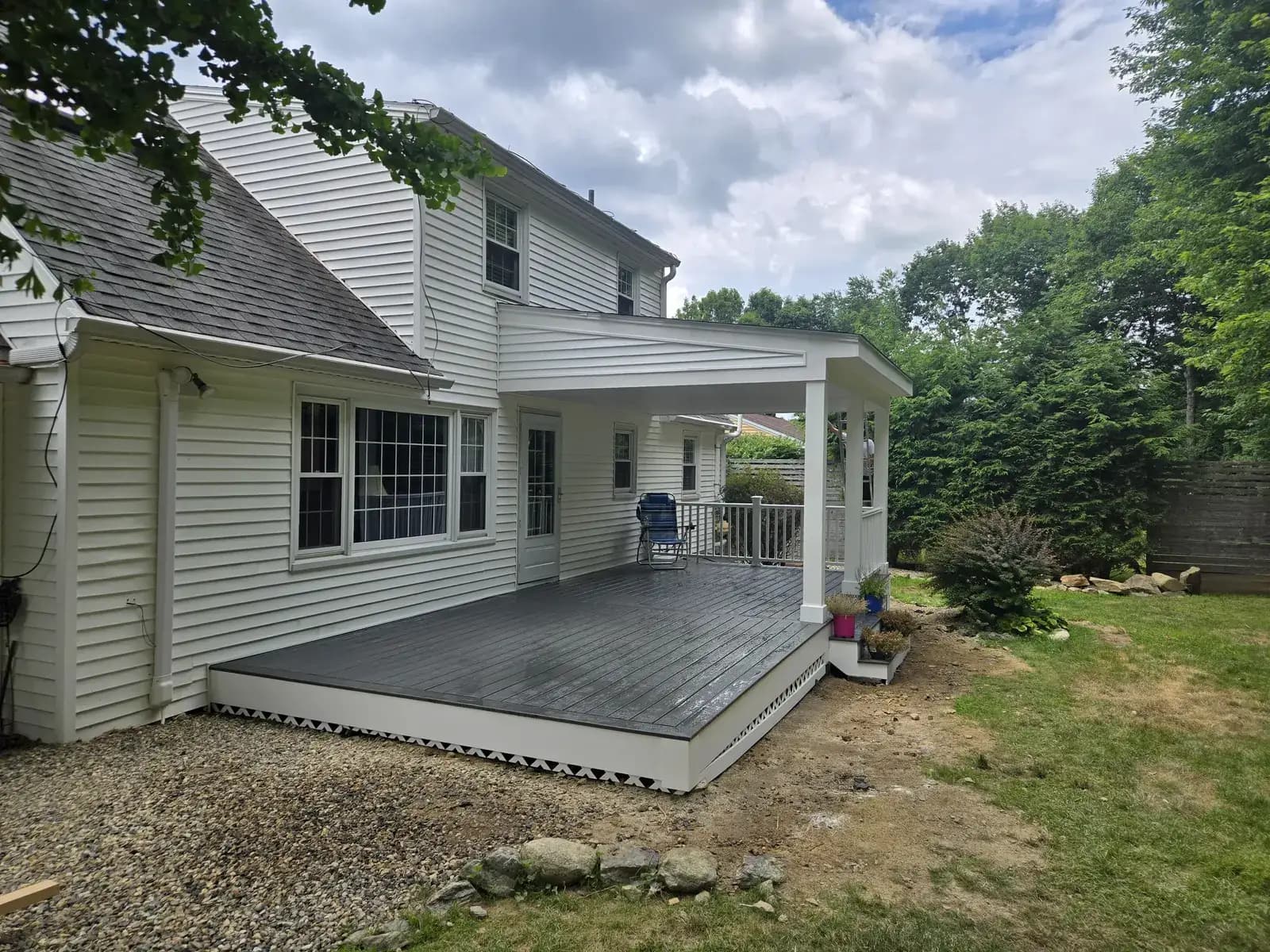 New gray deck with covered porch roof, white posts and railing built by Delane Construction