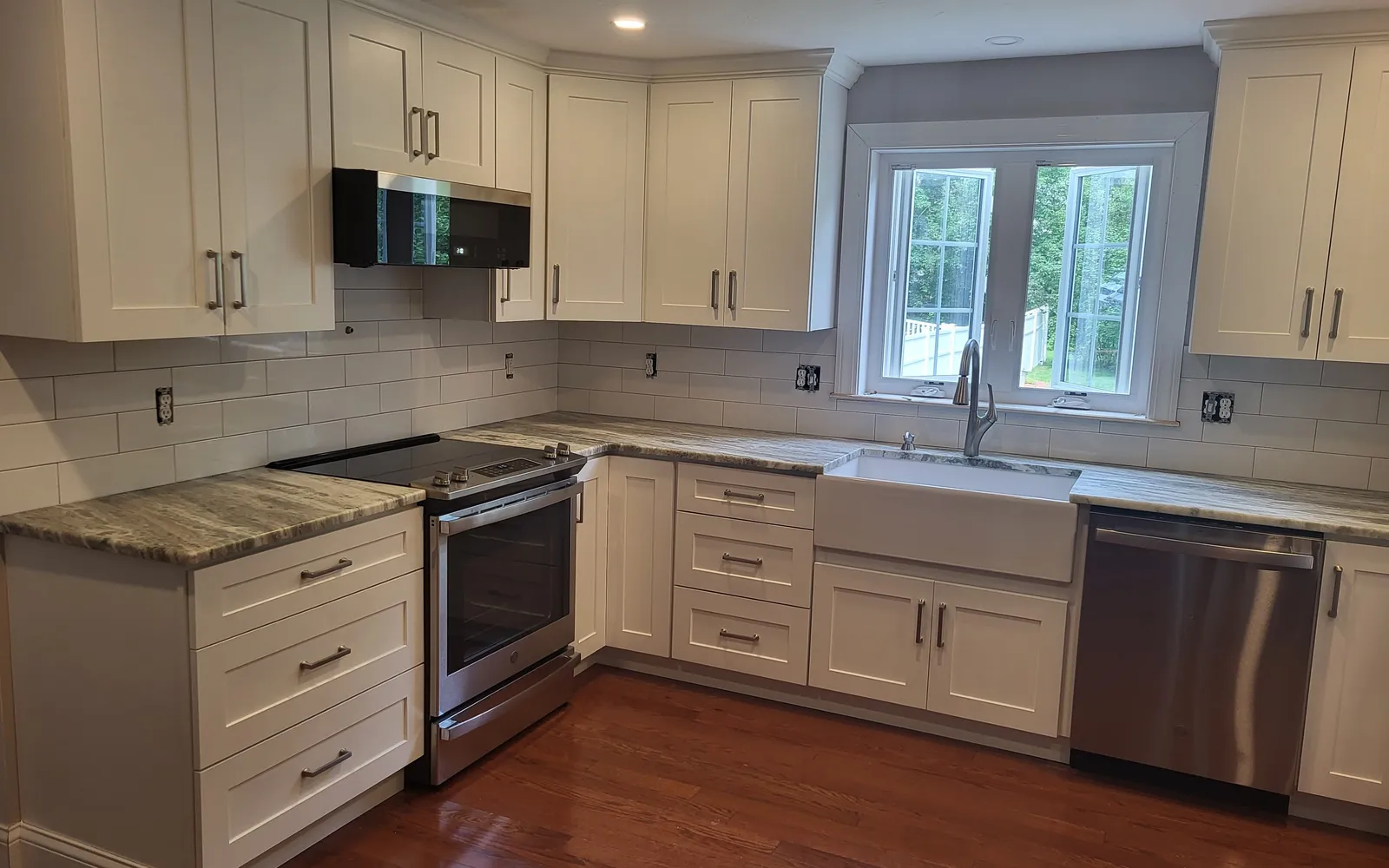 Cream kitchen with granite counters, farmhouse sink and stainless appliances