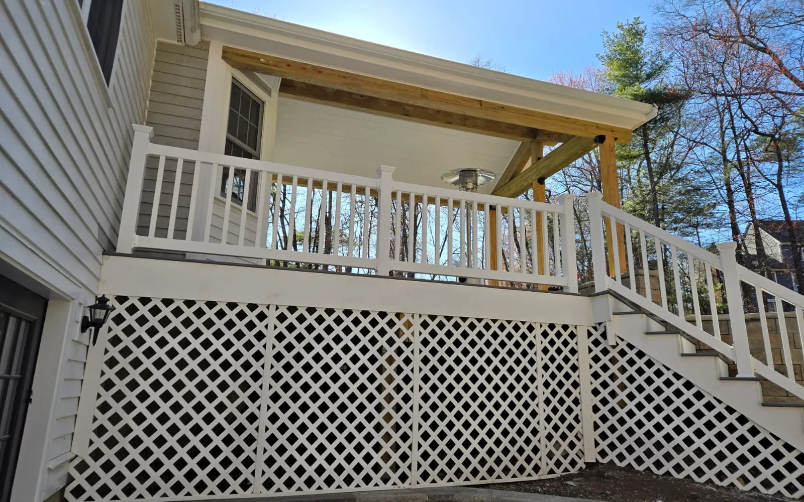 Raised deck with covered roof, white railing, stairs and lattice skirting