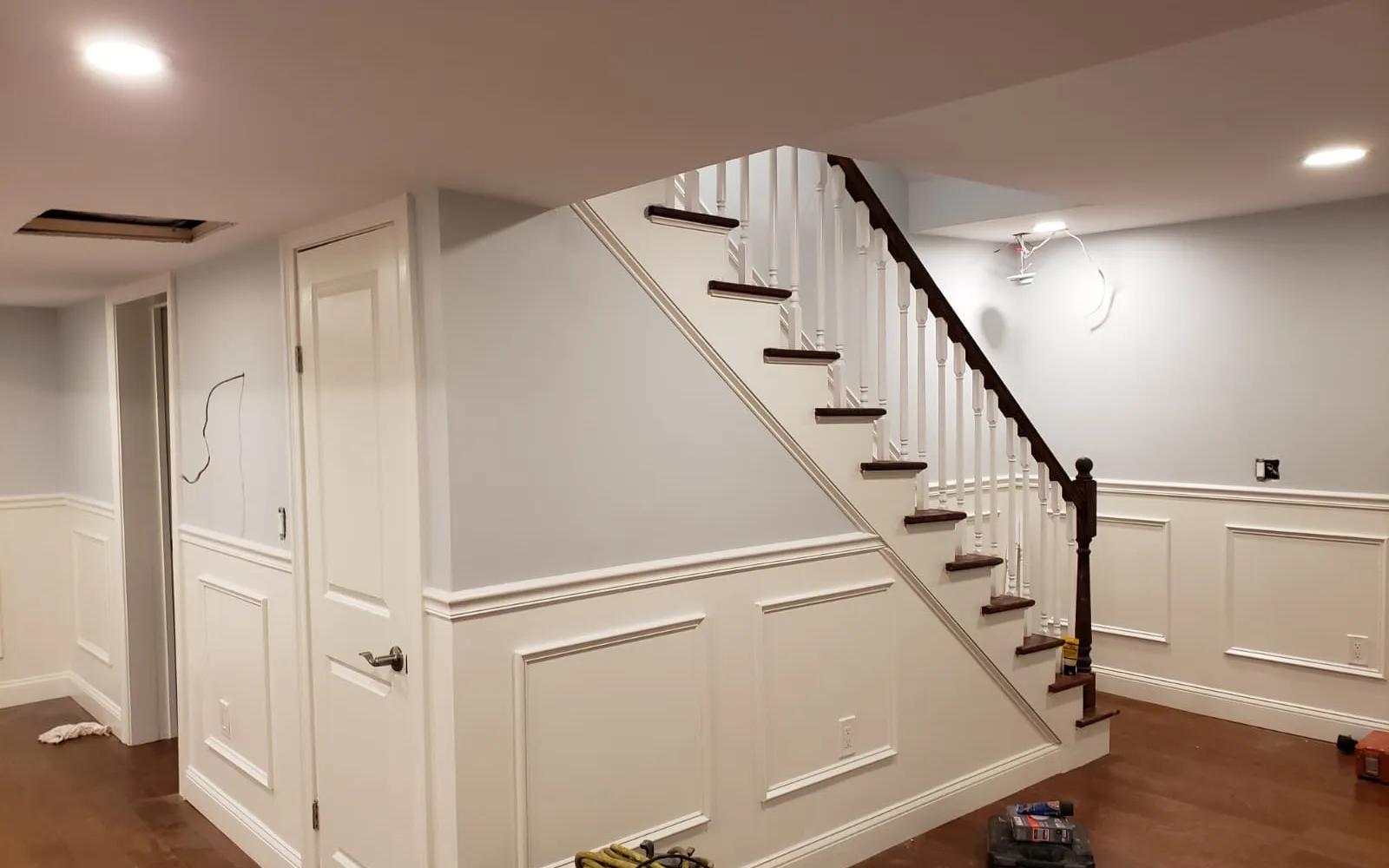 Finished basement with new stairs, wainscoting and recessed lighting