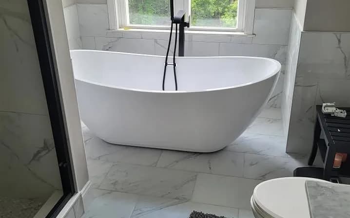 Bathroom remodel with a freestanding soaking tub and marble-look tile
