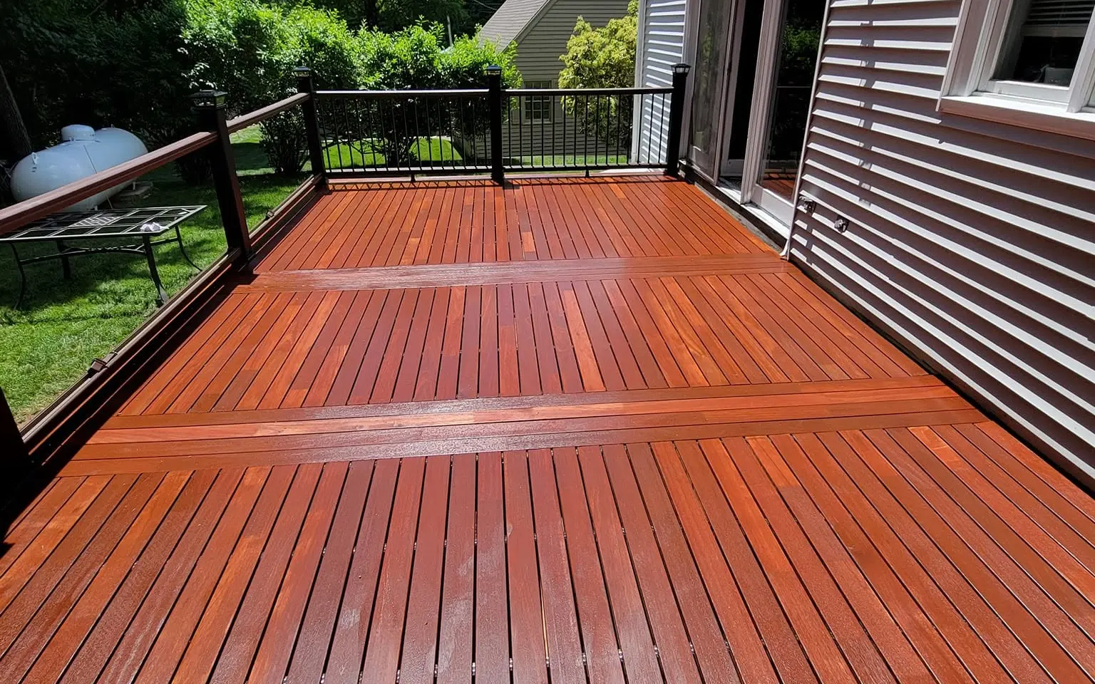 Hardwood deck with black metal railing on the back of a home