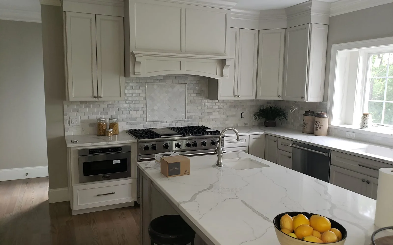 Remodeled kitchen with quartz island, range hood and gray cabinetry