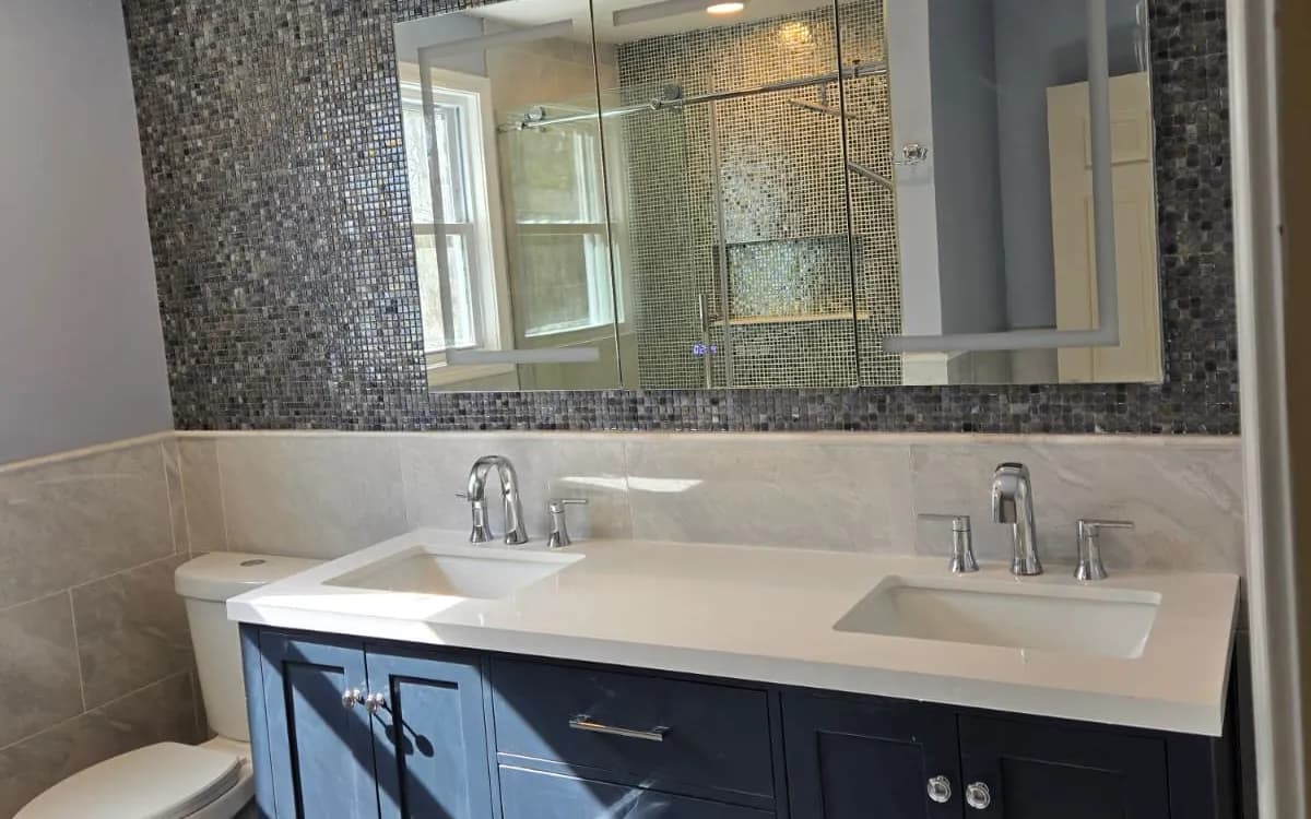 Bathroom remodel with navy double vanity, mosaic tile feature wall and large mirror