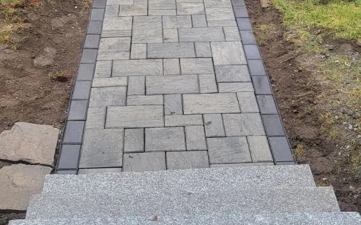 New paver walkway and steps with the Delane Construction van parked at the job